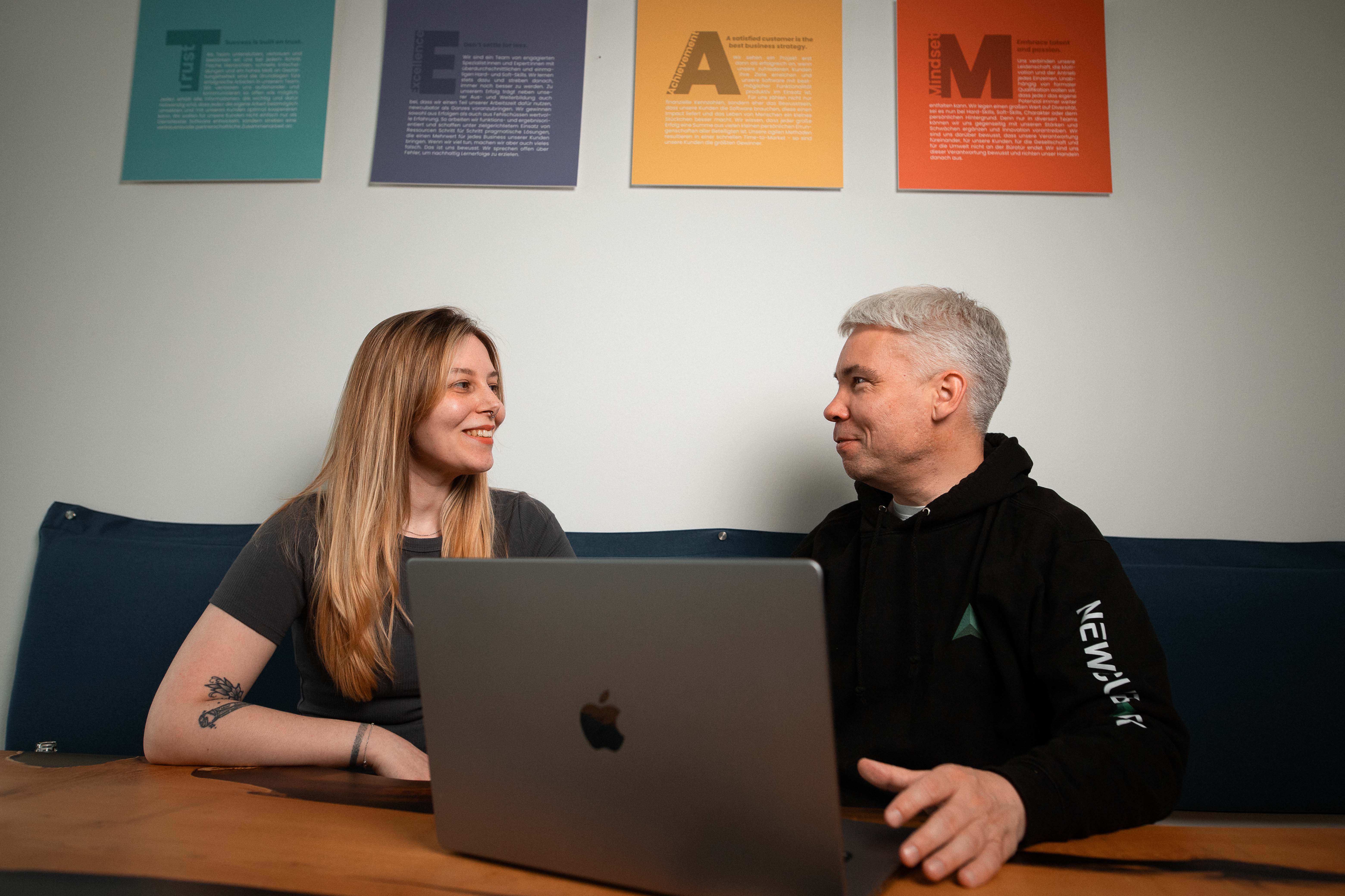 Zwei newcubator Teammitglieder sprechen direkt an einem Laptop über ein Projekt.