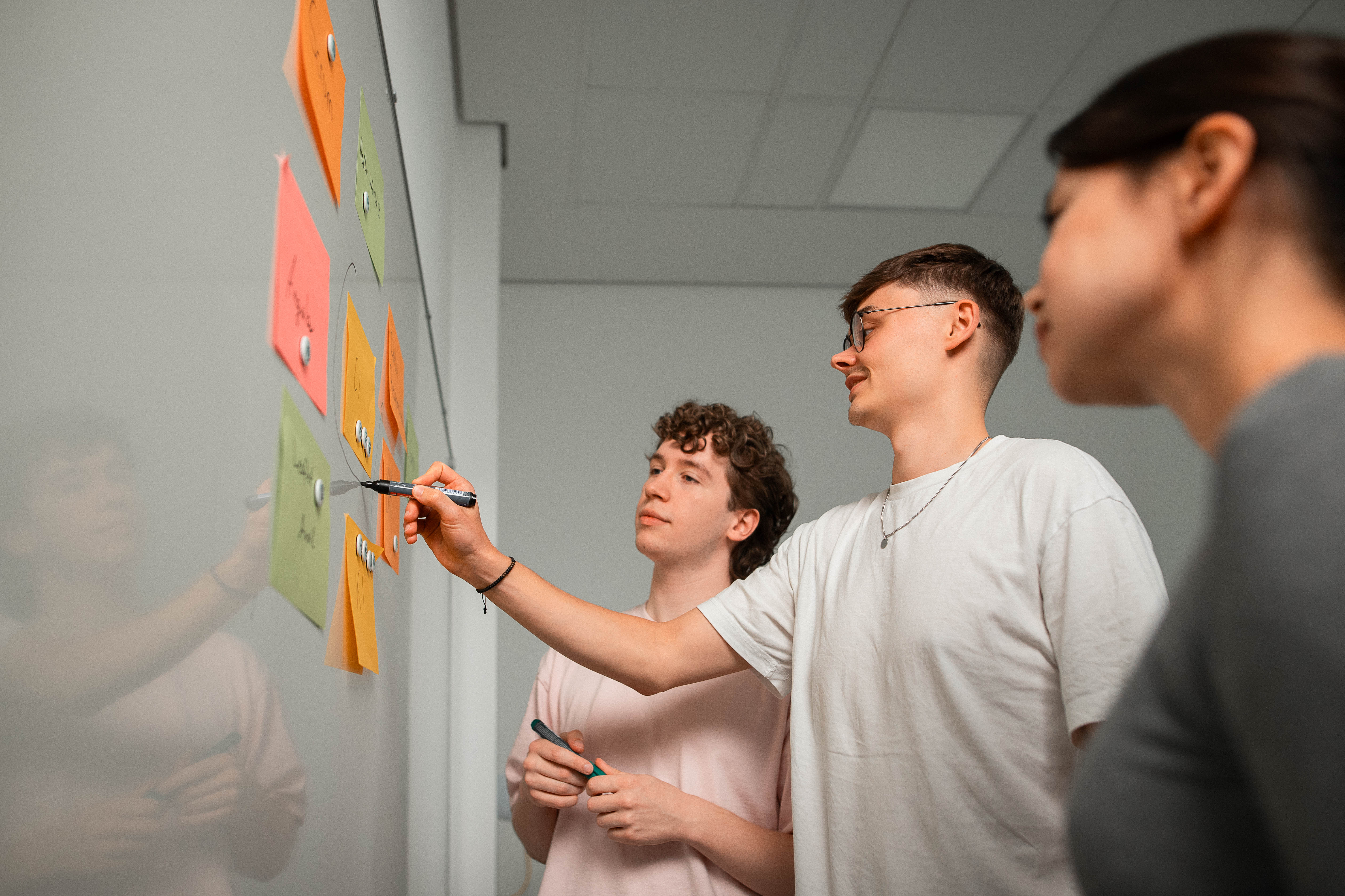 newcubator Teammitglieder strukturieren Anforderungen mit Notizen am Whiteboard.